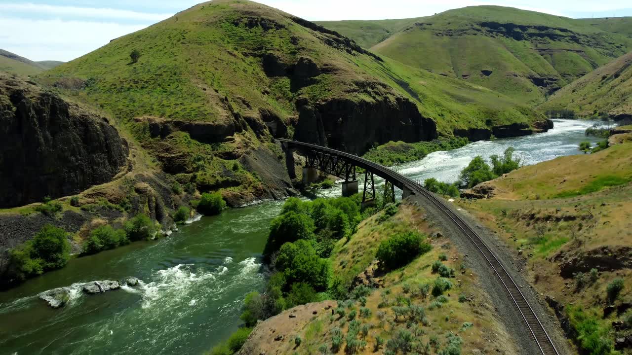US, Oregon, Maupin, Deschutes River, 2025-05-08 - Drone view on the Deschutes River of a train bridge at Twin Crossings which is two bridges and a tunnel. In north central Oregon in spring