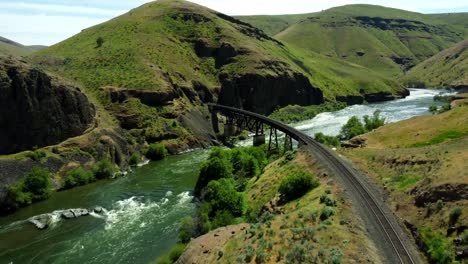 us, oregon, maupin, deschutes river, 2025-05-08 - drone view on the deschutes river of a train bridge at twin crossings which is two bridges and a tunnel. in north central oregon in spring