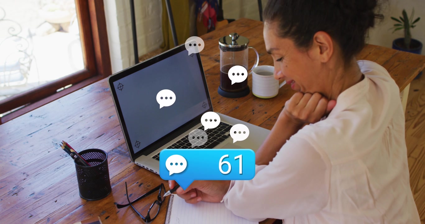 Animation of message icon over woman looking at laptop with copy space