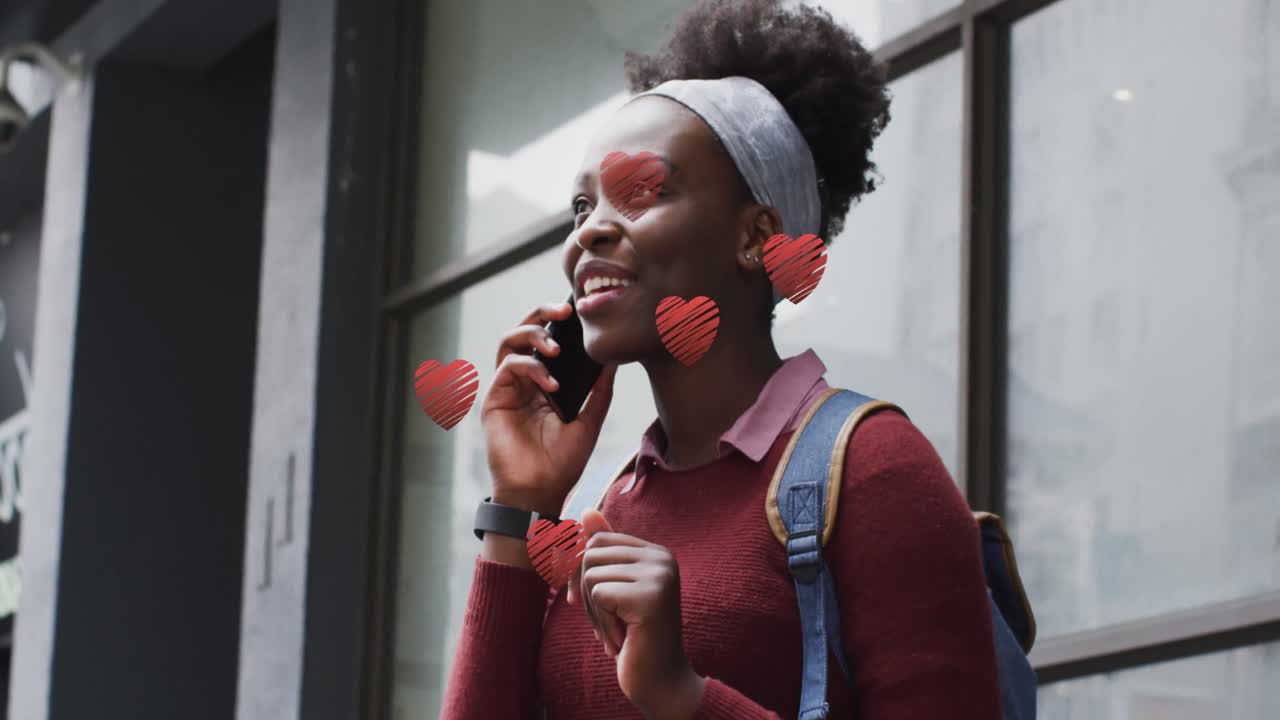 Animation af røde hjerter over afroamerikansk kvinde, der taler i smartphone.