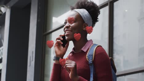 animation of red hearts over african american woman talking on smartphone