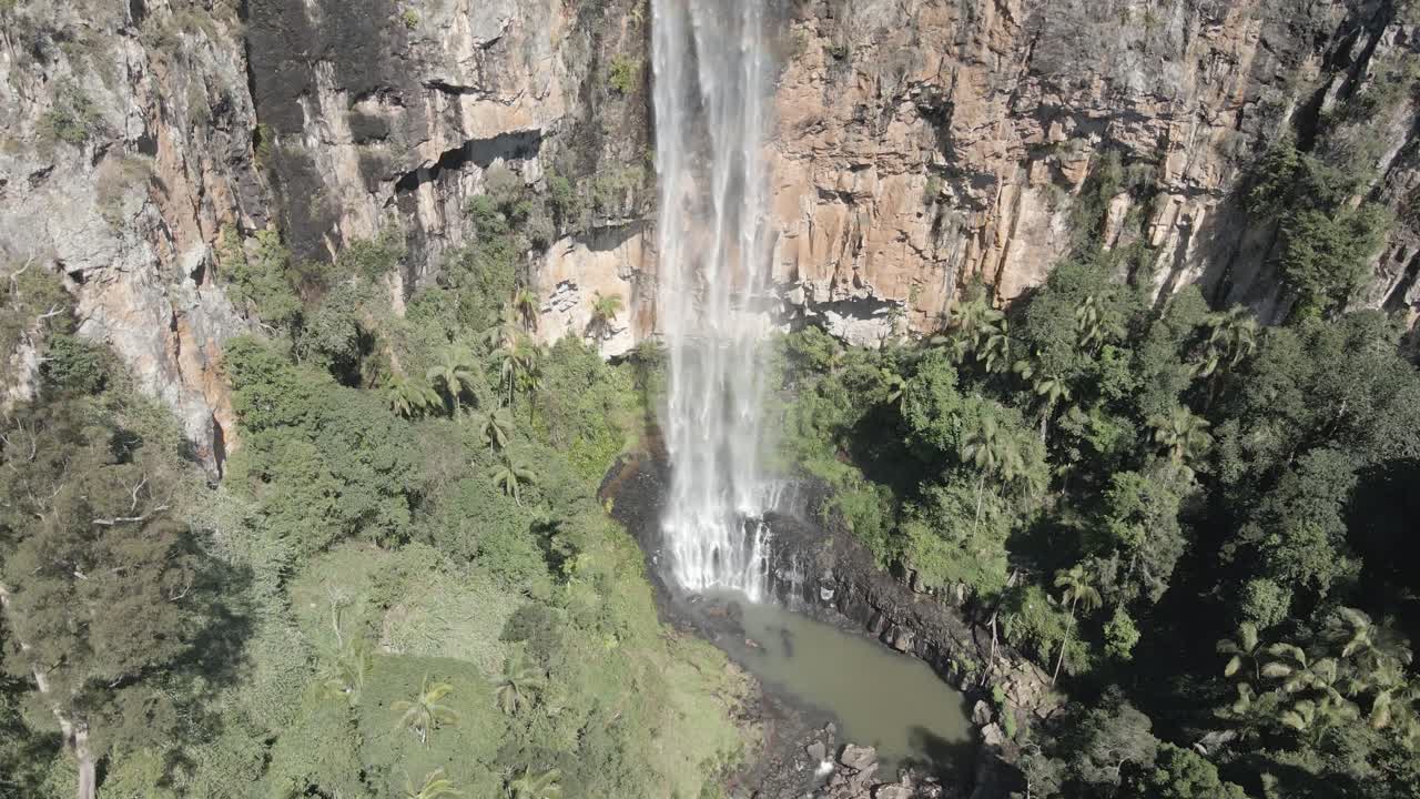 Stunning Aerial View of a Waterfall cascading down a Cliffside in a Lush Tropical Forest