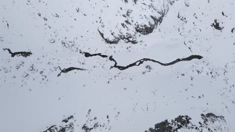 imágenes de drones de arriba hacia abajo de un río congelado en montañas nevadas