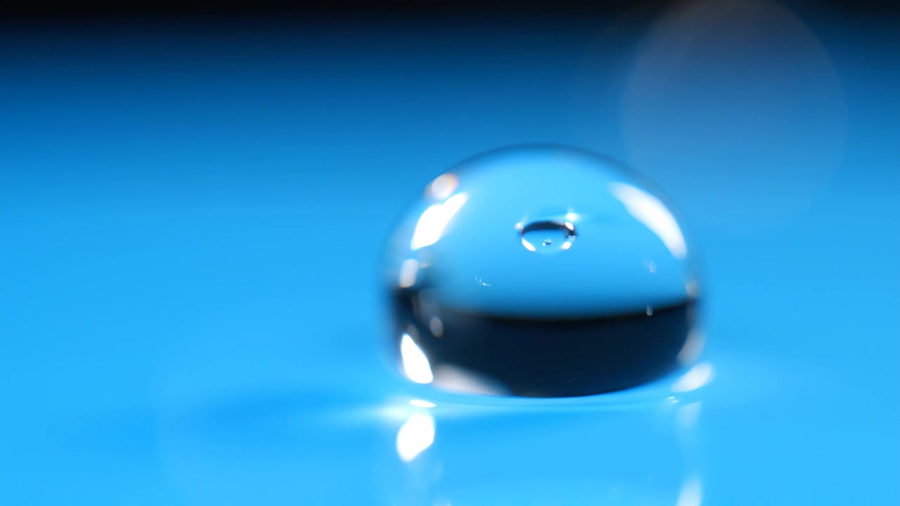 Macro Close-Up of Single Clear Water Droplet on Blue Background