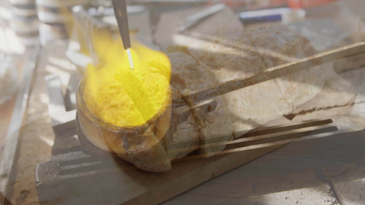 Heating metal with torch flame over rustic bread on wooden cutting board