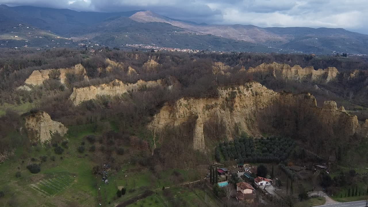 Approaching Aerial flying drone shot over prehistoric age canyons Le Balze natural reserve near Reggello. Tuscany, Chianti area. Italy. Winter season, partially sunny sunset