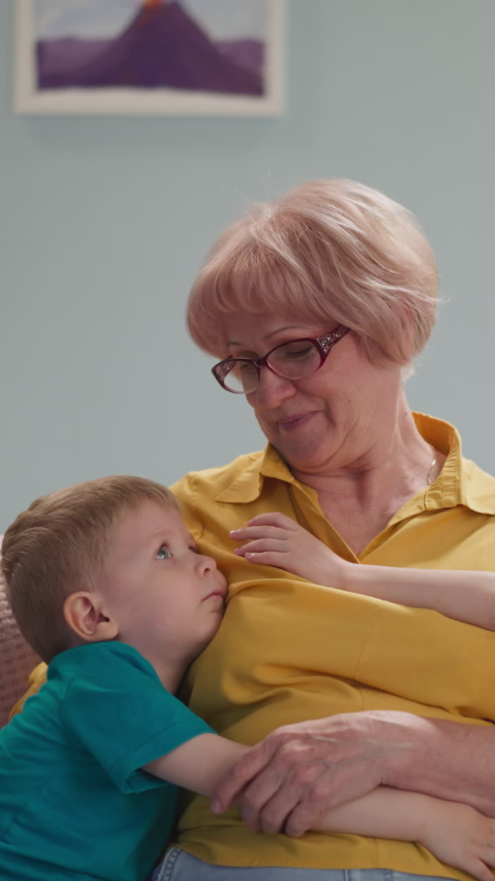 kids hug their beloved grandmother at home, the living room is bright, cozy and children's drawings are hanging, a friendly family, a family evening