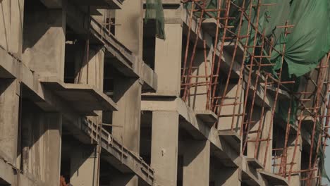andamios en el sitio de construcción en karachi con viento que sopla láminas verdes en el costado