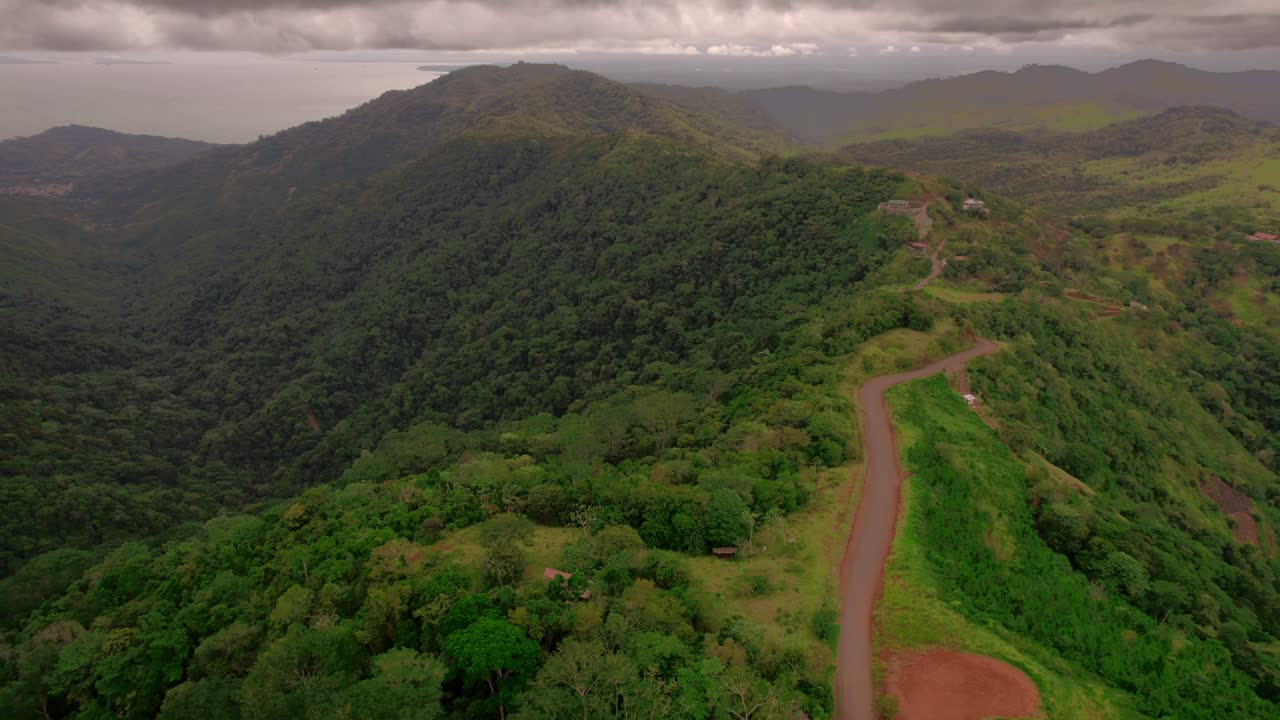 Aerial over magical mountainous landscape, green ambient with lot's of forest trees and road sliding over hill edge