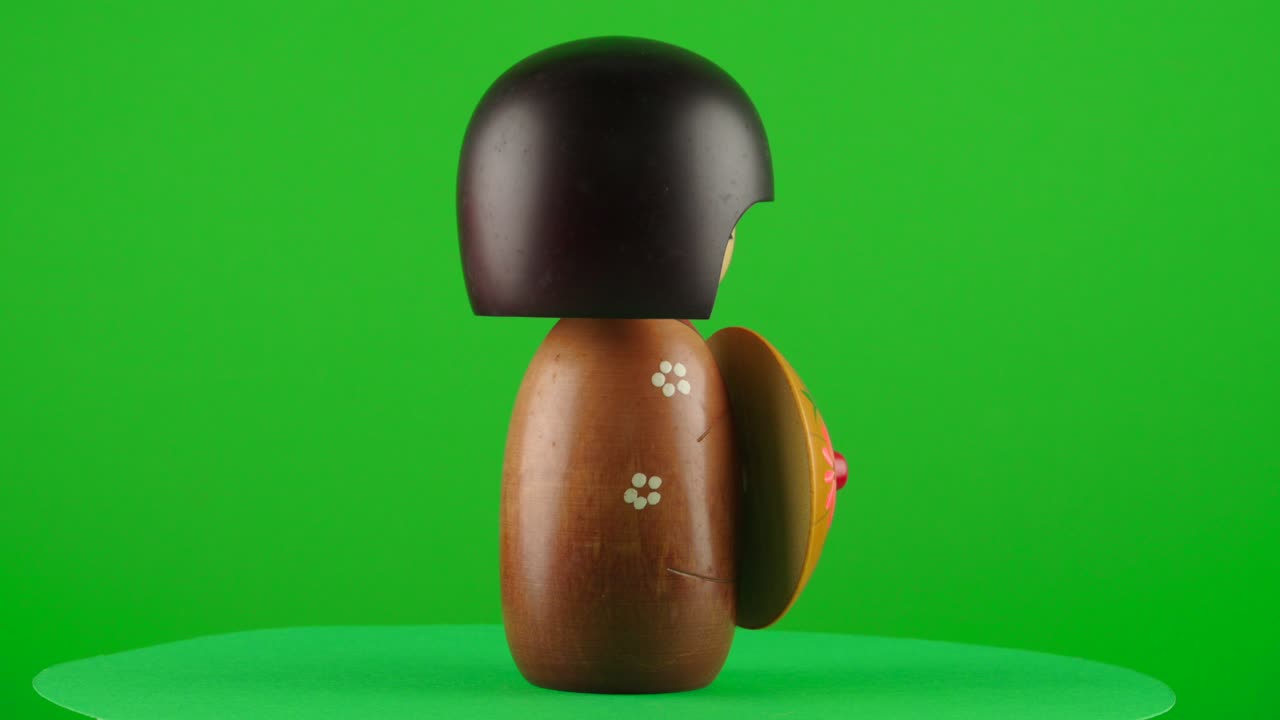 Maiko geisha kimono wooden doll handmade handcraft sakura umbrella in a turntable with green screen for background removal