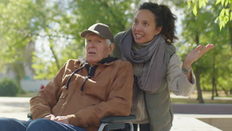elderly man in wheelchair and young woman on walk
