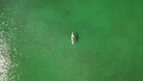 top-down view of person kayaking in the lake with calm green water at summer