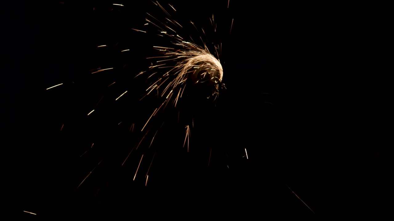el hombre trabaja la sierra circular sobre el acero. las chispas vuelan desde el metal caliente sobre un fondo negro.