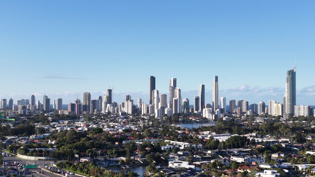 Inquadratura ampia statica di grattacieli urbani e quartieri residenziali sotto un cielo azzurro e limpido