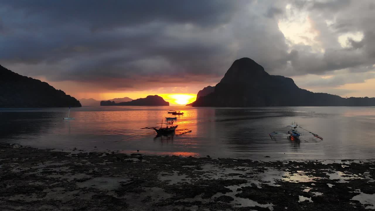 presenciar una hermosa puesta de sol sobre las olas en el nido, filipinas, con barcos a la deriva en el mar de luz naranja