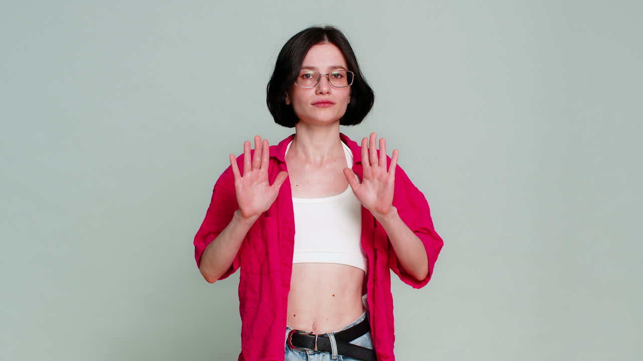 Young woman showing careful warning gesture with serious facial expression cautioning viewer beware