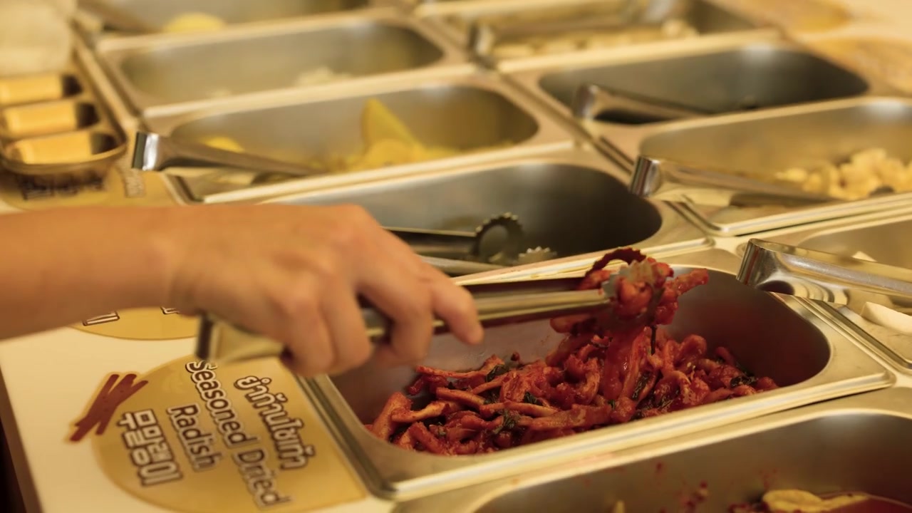 Primo piano di mani che usano pinze per servire ravanelli conditi da contenitori da buffet in acciaio inossidabile