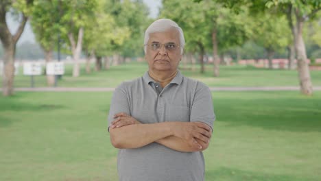 Confident-Indian-old-man-standing-crossed-hands-in-park