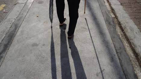 back view of a disabled woman walk with support stick