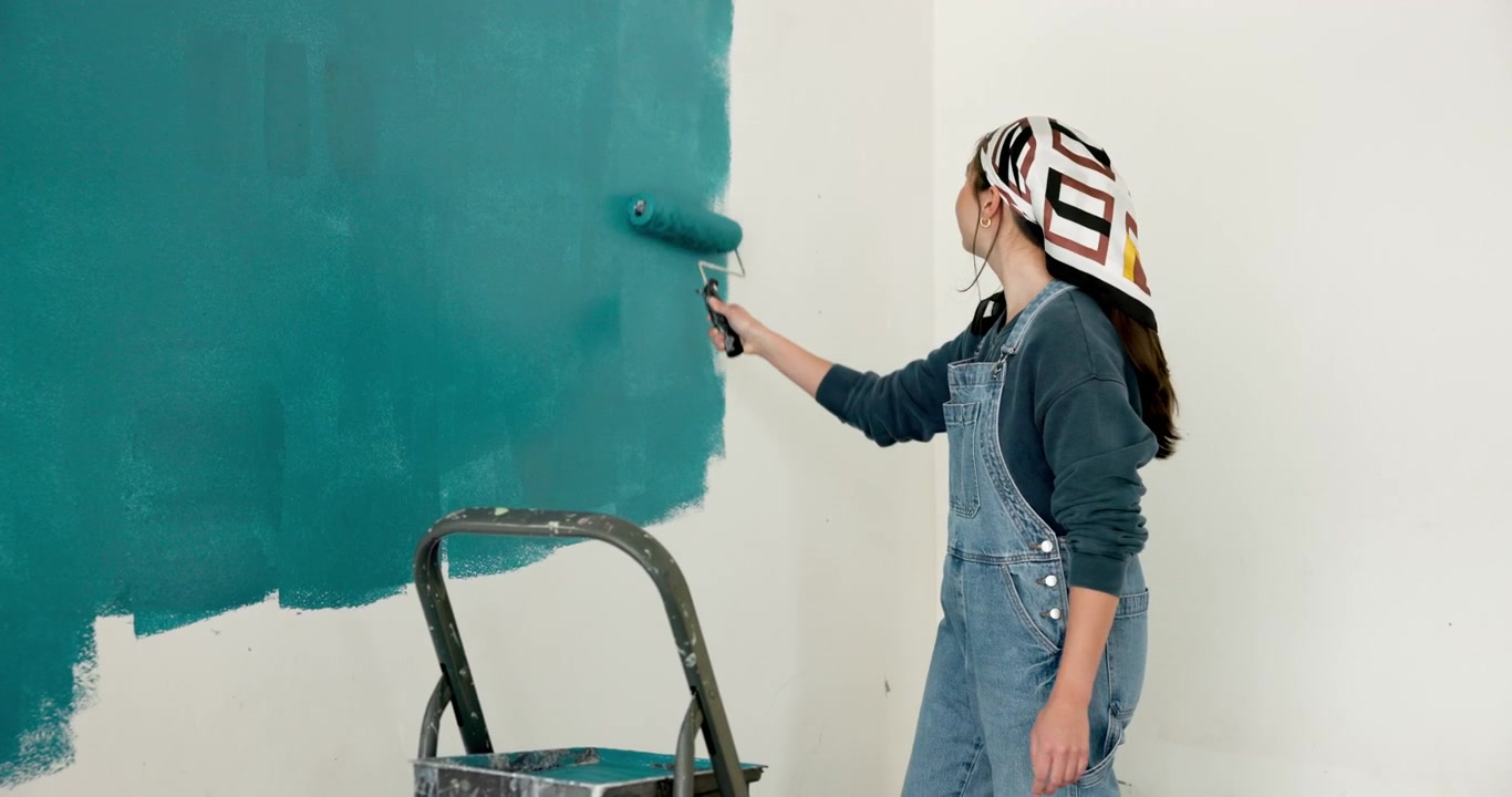Jovem mulher pintando uma parede com um rolo em um quarto