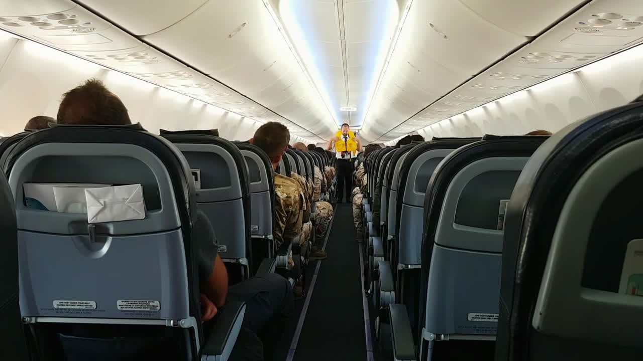 Tripulação de cabine demonstra aos passageiros o uso do colete salva-vidas