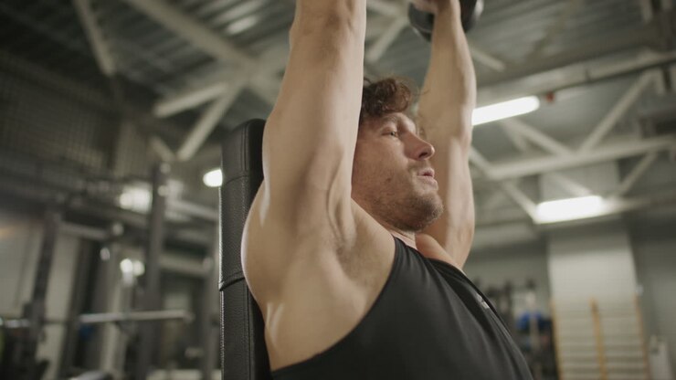 Male Bodybuilder Doing Dumbbell Overhead Press Exercise in Gym