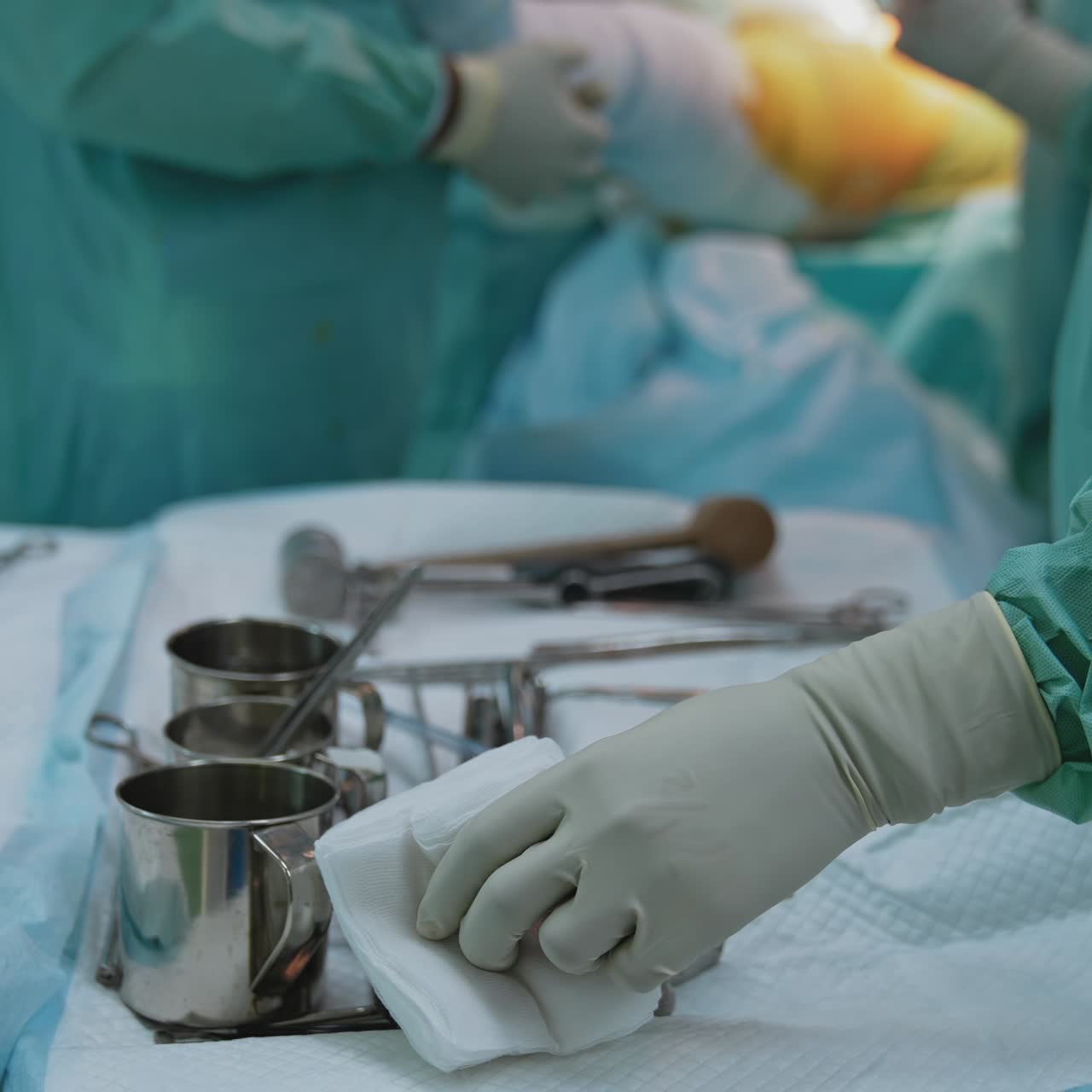 Nurse assisting doctors surgeons during surgical procedure. Sterile instruments on table and medical experts performing surgery in the blurred background in operating theater