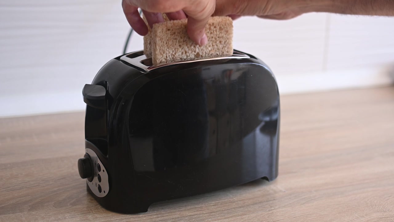 Placing bread slices into a toaster to make breakfast toast