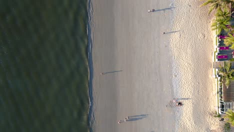 Tourists-enjoying-walking-on-the-beach-at-sunset-with-lush-green-tropical-forest-in-the-background