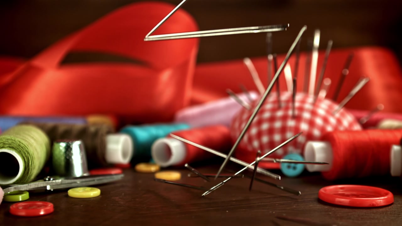 Sewing Needles Falling onto a Table with Craft Supplies in Slow Motion