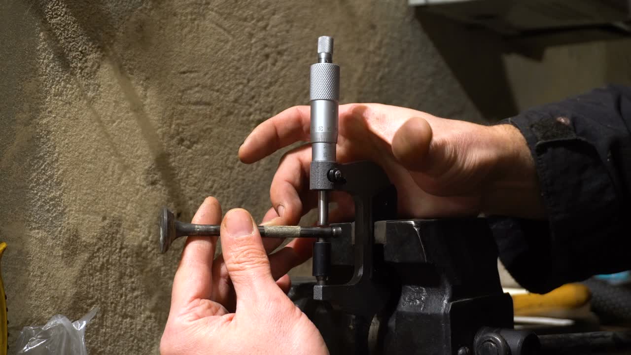 el hombre mide la válvula del motor. herramienta de micrómetro