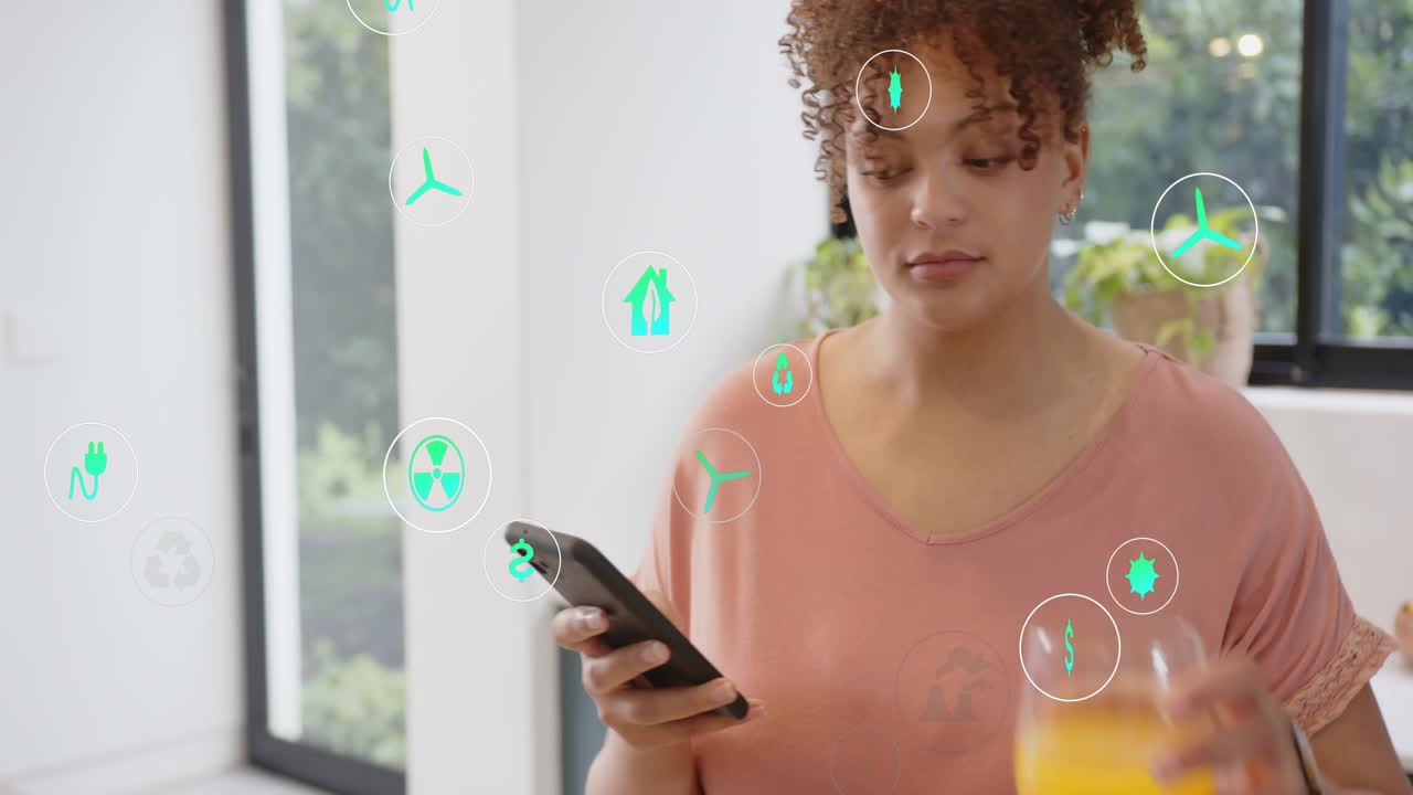 Woman standing kitchen tapping phone and activating floating green icons while checking energy data