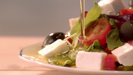 pouring olive oil dressing over fresh salad, macro, slow motion