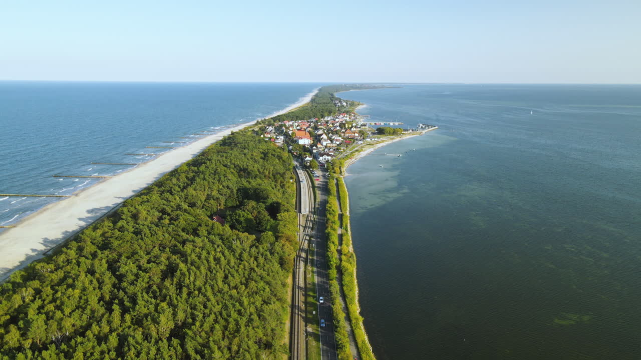 Luftdolly-skud af grøn skov, sandstrand, jernbanespor og lille by i baggrunden