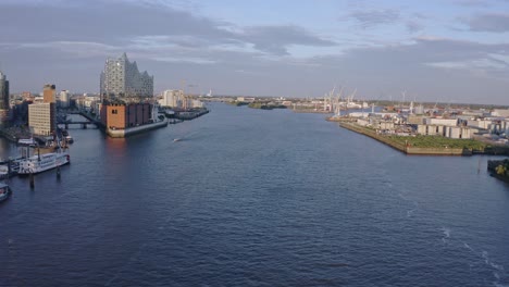 Flying-upstream-on-the-River-Elbe-with-the-Elbphilharmonie-concert-hall-on-the-Gasbrook-Peninsula-and-the-city-of-Hamburg,-Germany