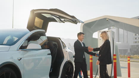 gente de negocios abrazándose en la estación de carga de ev