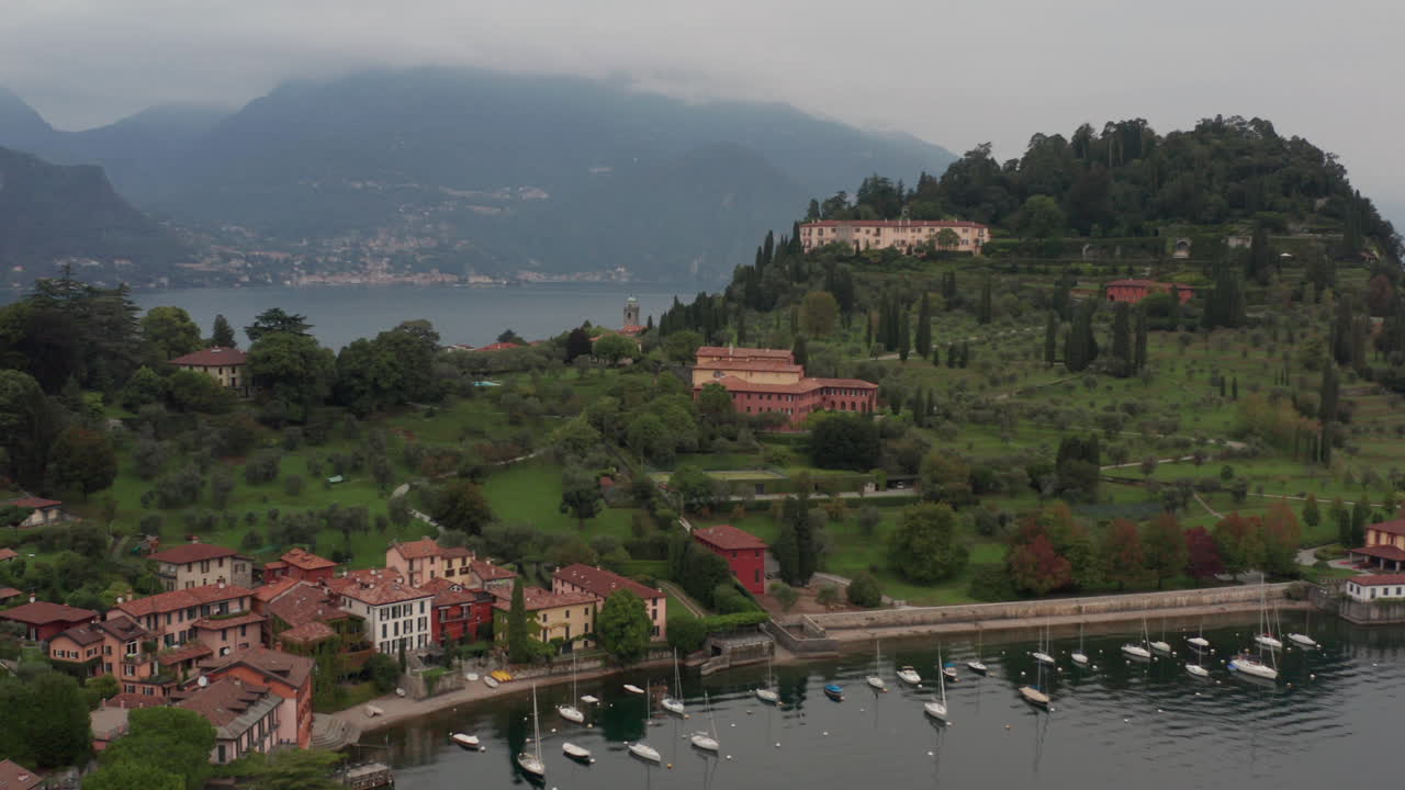 aéreo sobre una montaña verde cerca de la ciudad de bellagio, italia y que revela un vasto e impresionante lago