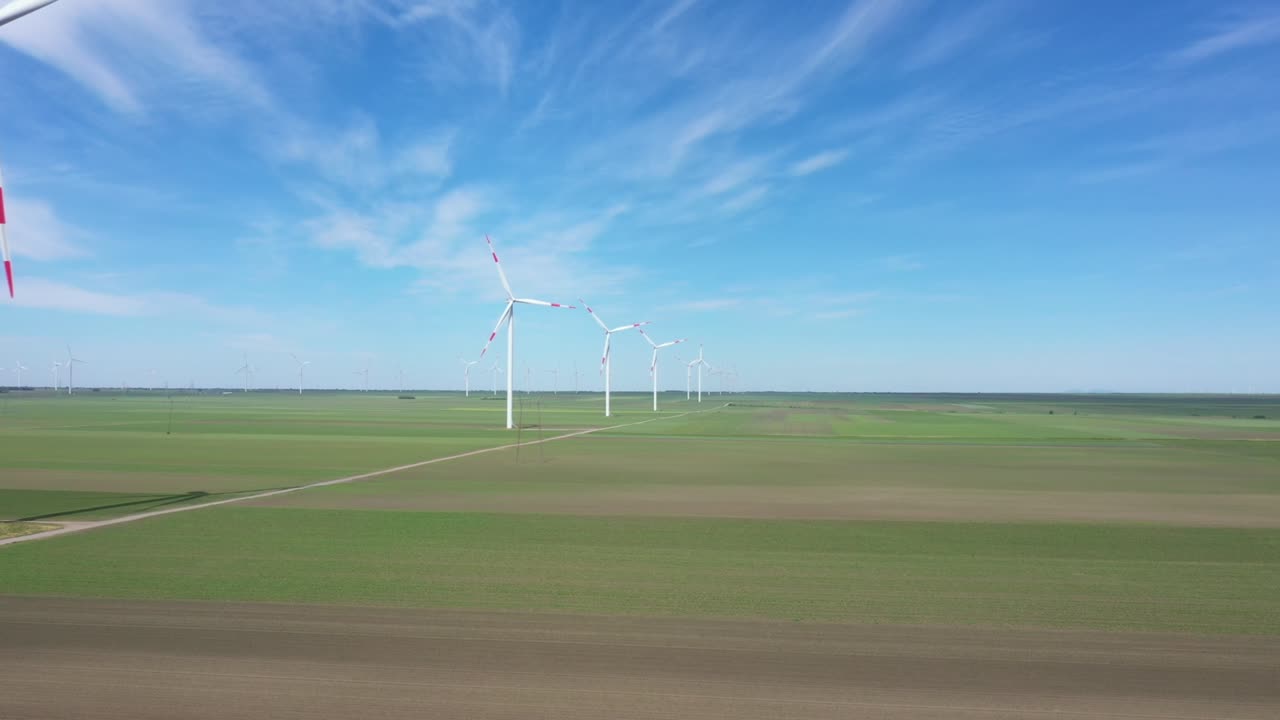 View of several windmills, wind generators, turbines, producing renewable clean energy by converting kinetic energy