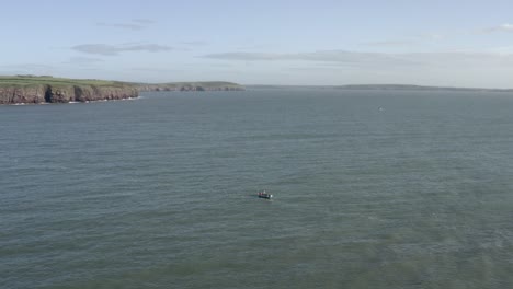 sea aerial: fisherman in open boat sets lobster traps near irish coast