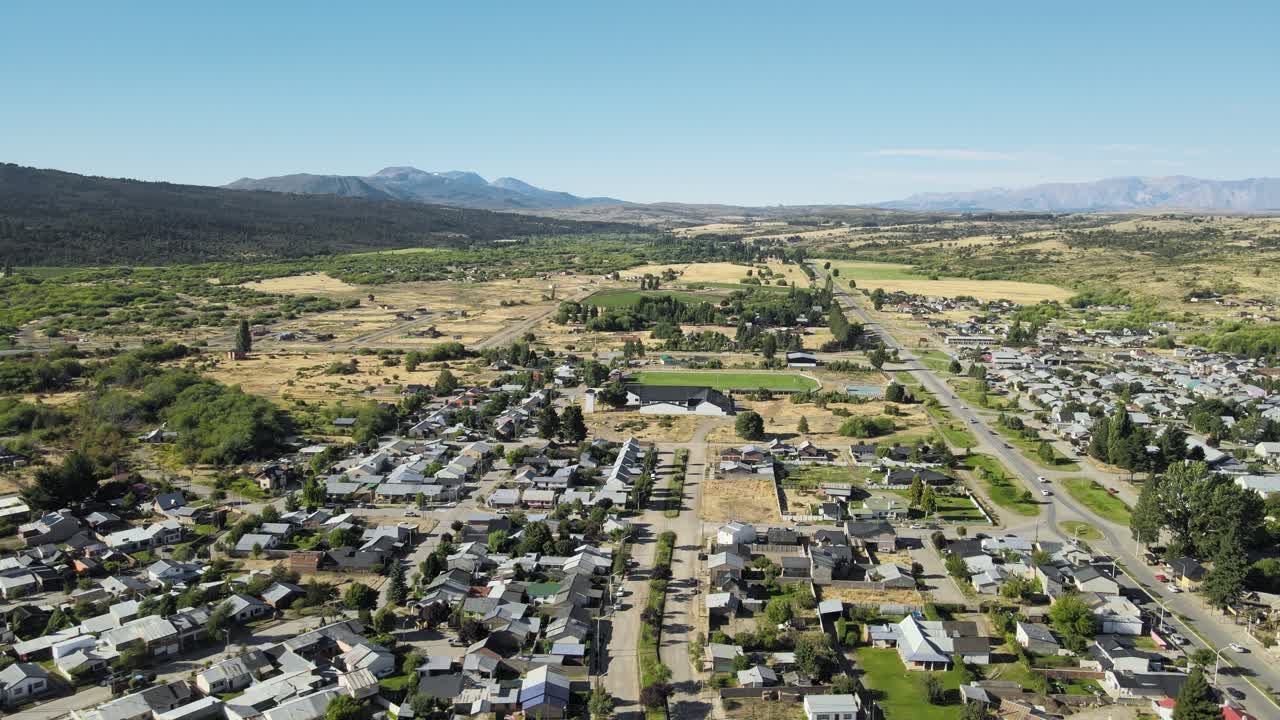vuelo aéreo sobre casas de la ciudad de trevelin en un valle en medio de las montañas andinas, patagonia argentina