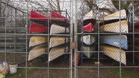 Canoes-stored-stacked-organized-behind-a-locked-fence-during-autumn-fall-season