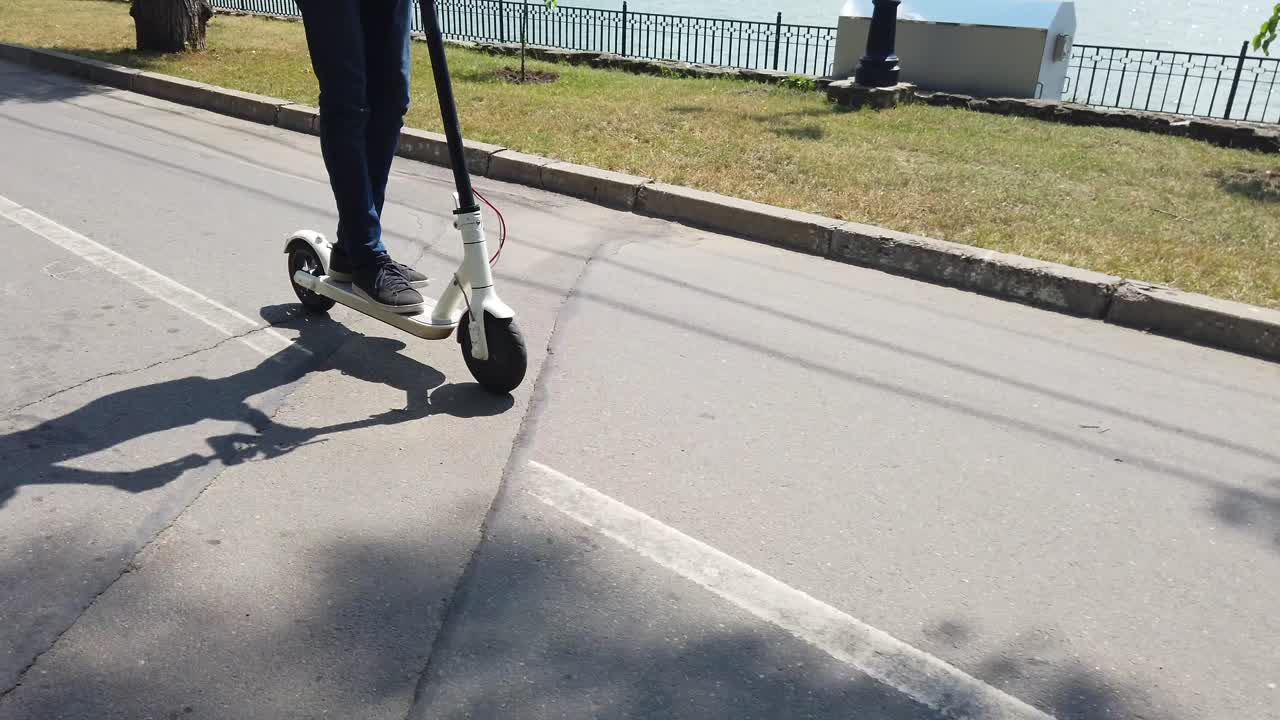 公園で白い電動スクーターに乗る男性。背景には人々。