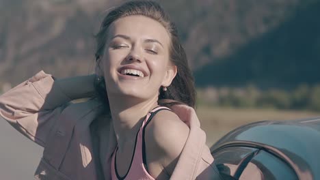 happy woman plays with hair leaning out of car window