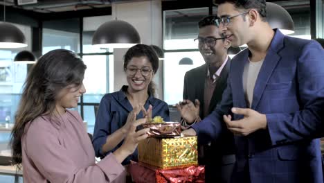 office colleagues smiling, clapping and celebrating success by giving gift boxes