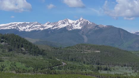 beautiful aerial panoramic of snowy capped mountain peak and evergreen forest