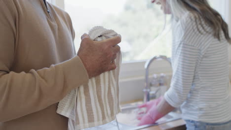 Middle-aged-caucasian-couple-washing-dishes-in-kitchen-at-home,-slow-motion