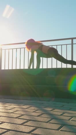 silhouette of woman bending down near railing with sunlight creating lens flare effects