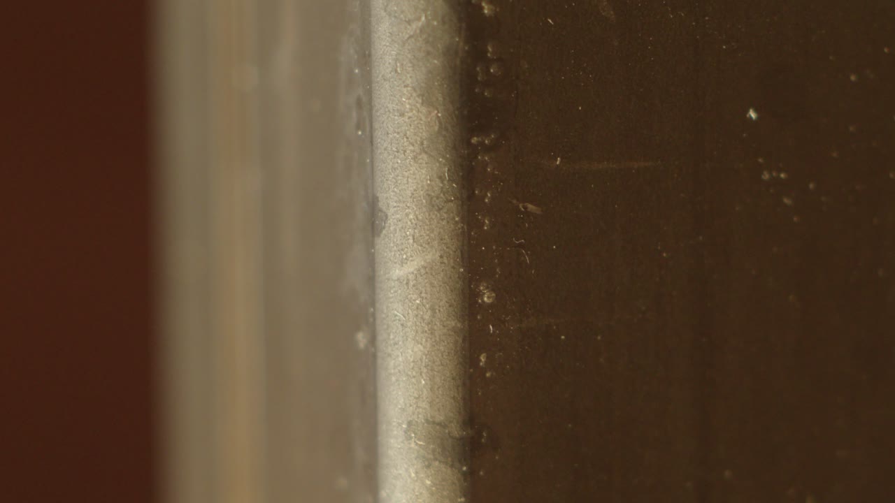 Close-up macro of a dark wood block with visible grain and warm highlights. Ideal for texture, product, or interior visuals