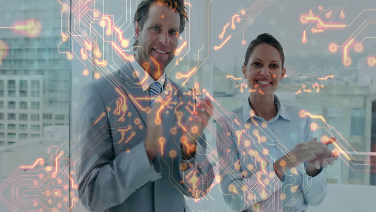 male executive and female colleague applauding in office, circuit graphics showing technology theme