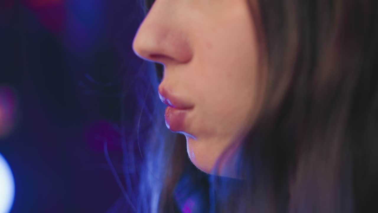 Extreme close up of woman gently placing popcorn in mouth, fingers touching lips with soft lighting reflecting on skin and nails, capturing quiet moment of snacking in relaxed setting